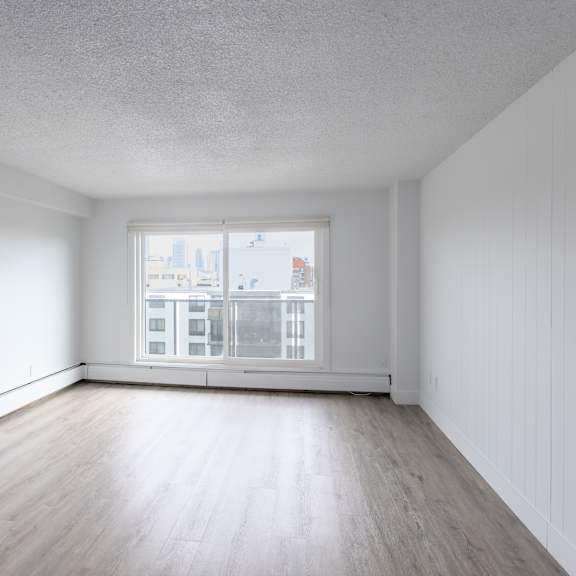 a large empty room with a window overlooking a cityscape.