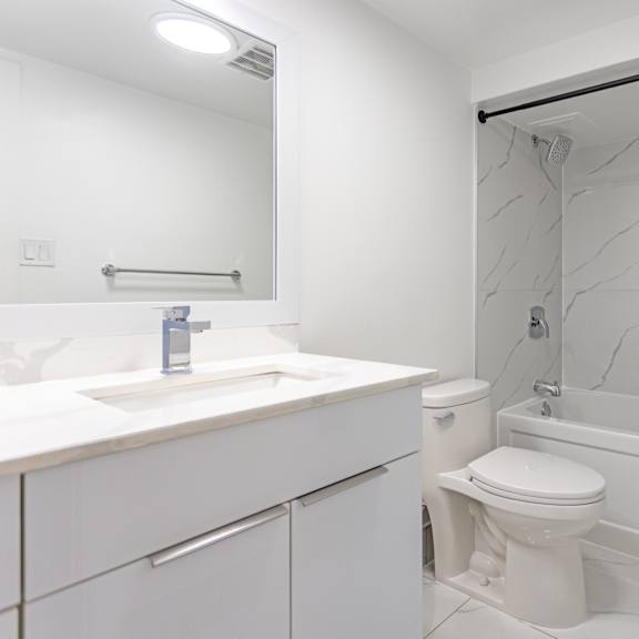 a white bathroom with a sink, toilet and bathtub.