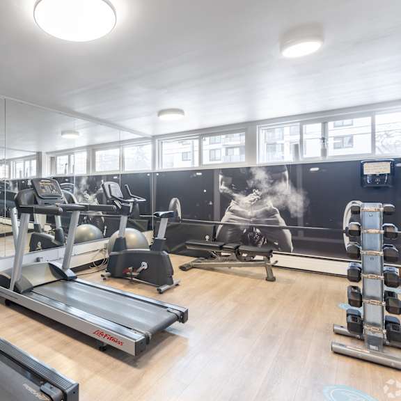 a gym with treadmills, elliptical machines, and other exercise equipment.