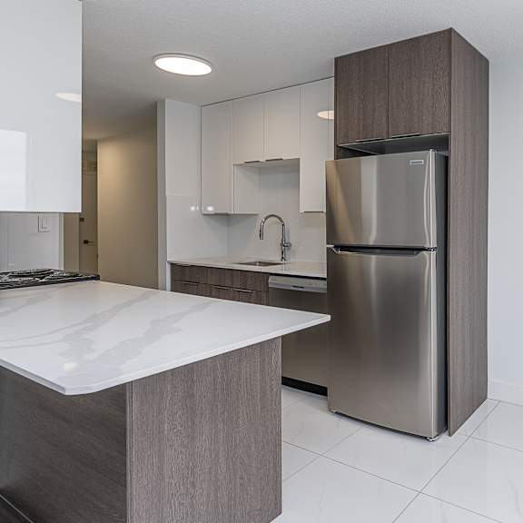 a modern kitchen with a stainless steel refrigerator and a white countertop.
