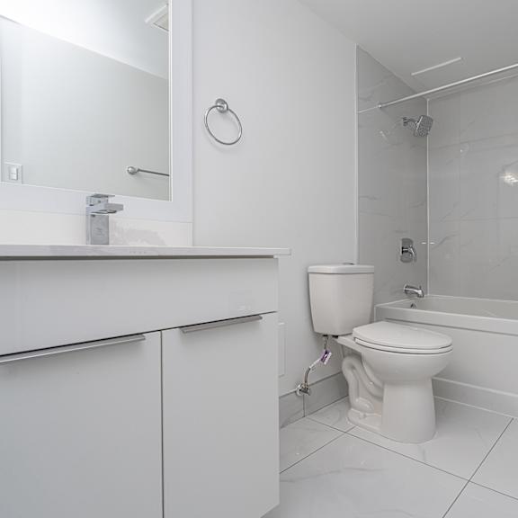 a white bathroom with a toilet, sink, and shower.