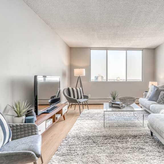a living room with a grey couch, a striped chair, and a television.