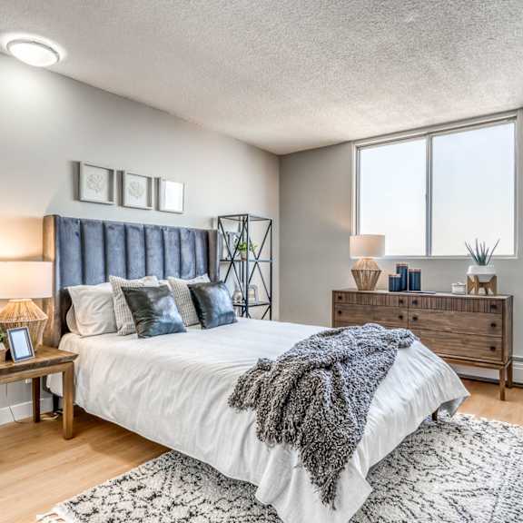 a bedroom with a bed, nightstand, and a window.