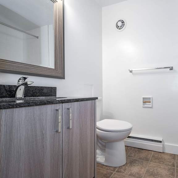 a bathroom with a toilet, sink, and mirror.