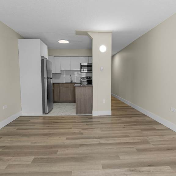 a kitchen area with a refrigerator, sink, and cabinets.