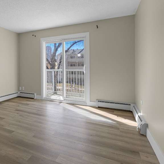 a room with wooden flooring and a sliding glass door leading outside.