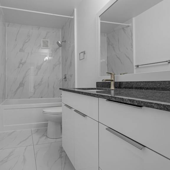 a white bathroom with a marble shower and toilet.