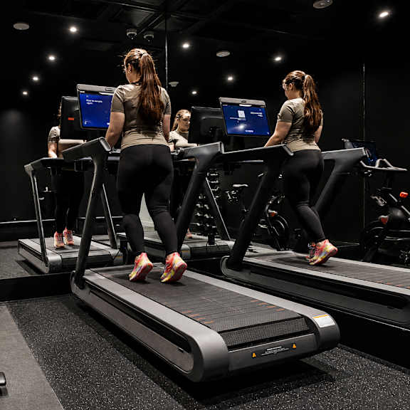 three women are running on treadmills in a gym.