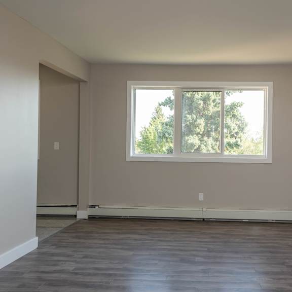 a room with a large window and wooden flooring.
