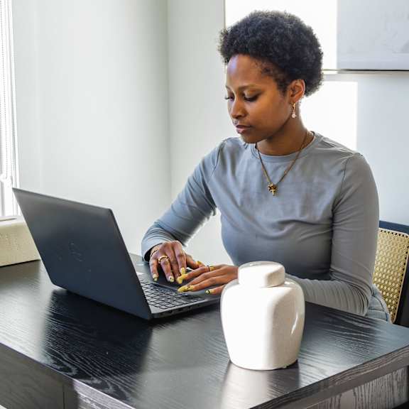 a woman is typing on a laptop at a desk.
