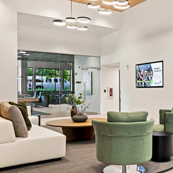 a modern living room with a white couch, green armchairs, and a glass door leading to a balcony.