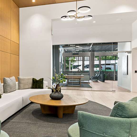 a modern living room with a white sofa, green armchairs, and a wooden coffee table.