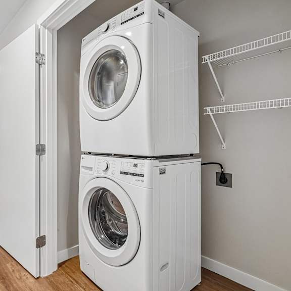 a white washing machine is stacked on top of another white washing machine in a room with white walls.