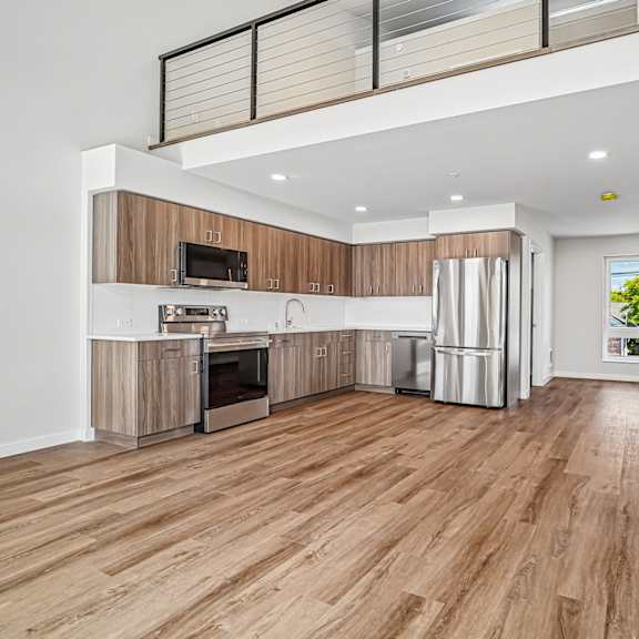 a spacious kitchen with wooden floors and white walls.
