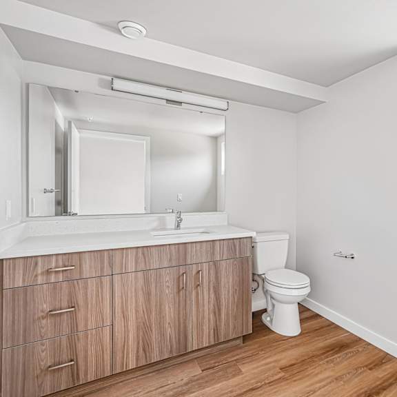 a bathroom with a toilet, sink, and mirror.
