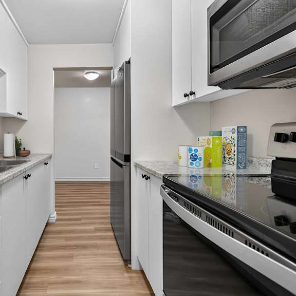a kitchen with white cabinets and a marble countertop.