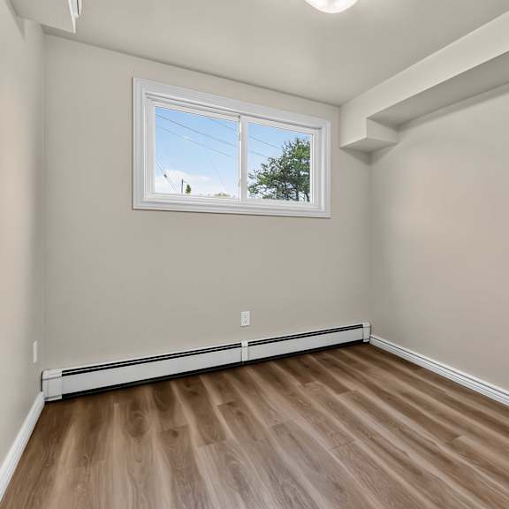 a room with a window and wooden flooring.