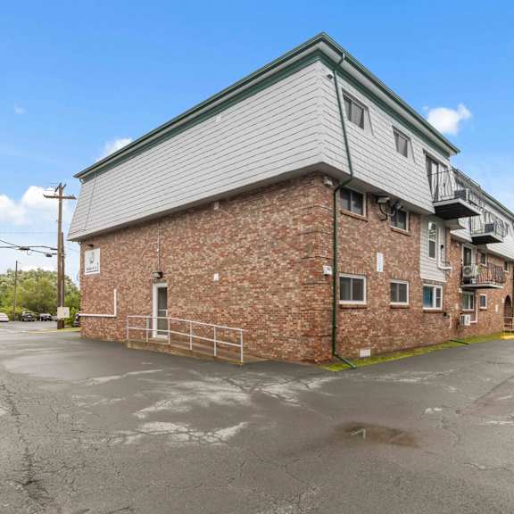 a parking lot in front of a brick building with a green roof.