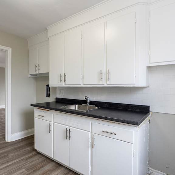 a kitchen with white cabinets and a black countertop.