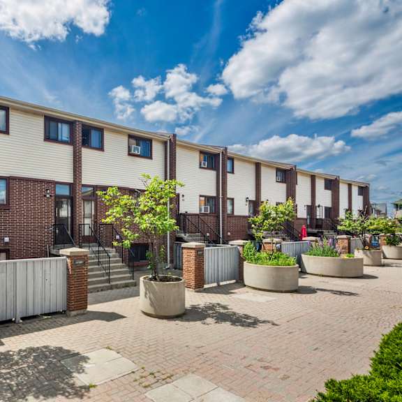 a sunny day at a residential area with apartment buildings and potted plants.