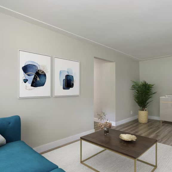 a living room with a blue couch, a coffee table, and two framed artworks on the wall.