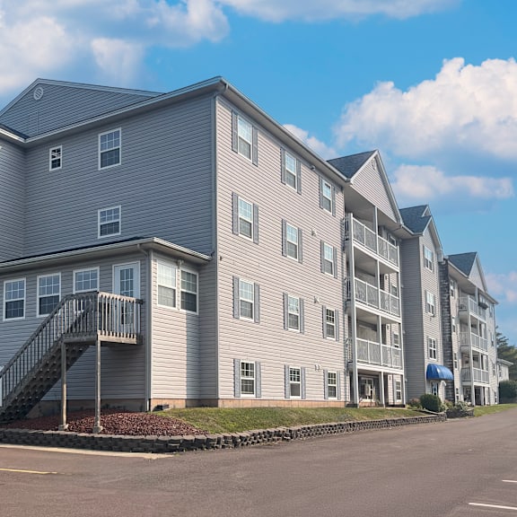 a large apartment building with a parking lot in front.