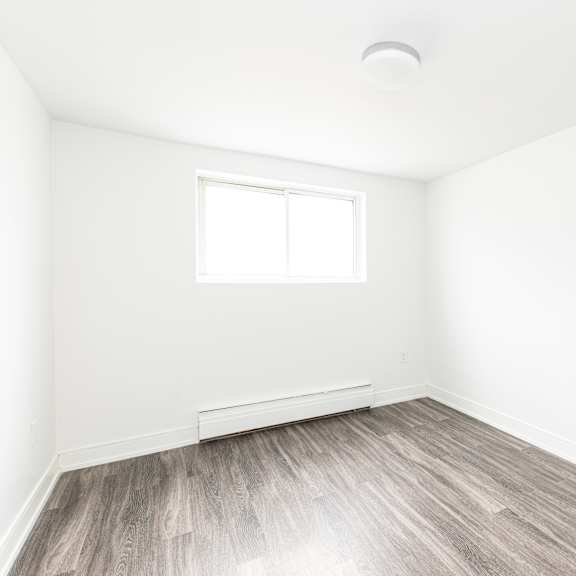 a room with a window and wooden flooring.