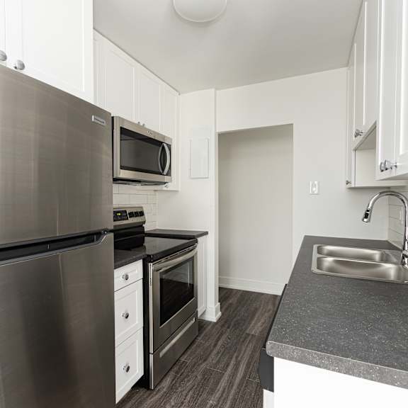 a modern kitchen with a stainless steel refrigerator, microwave, oven, and sink.