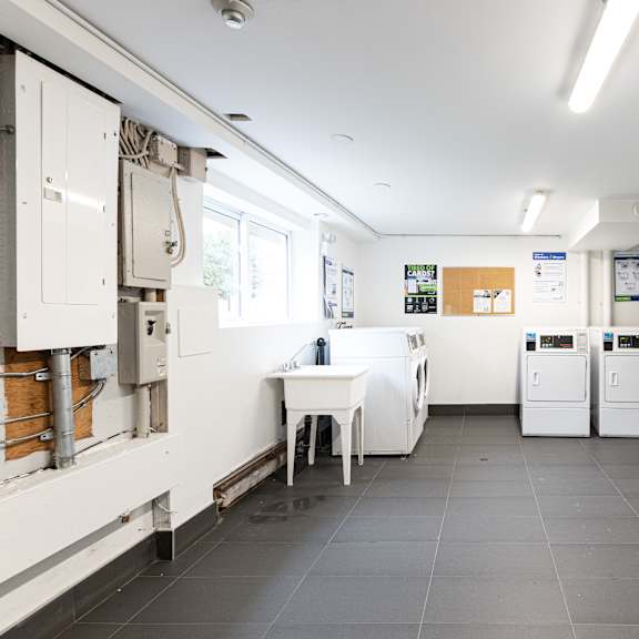 a clean, empty kitchen with white cabinets and a black trash can.