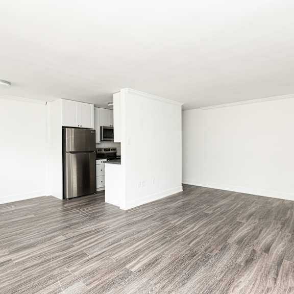 a kitchen with a stainless steel trash can and a wooden floor.