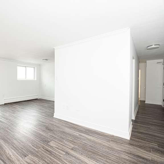 a spacious room with wooden flooring and white walls.