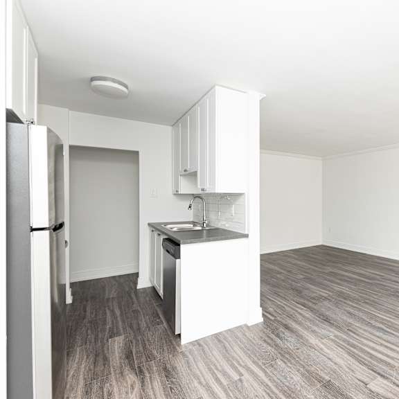a kitchen with a refrigerator, sink, and cabinets.