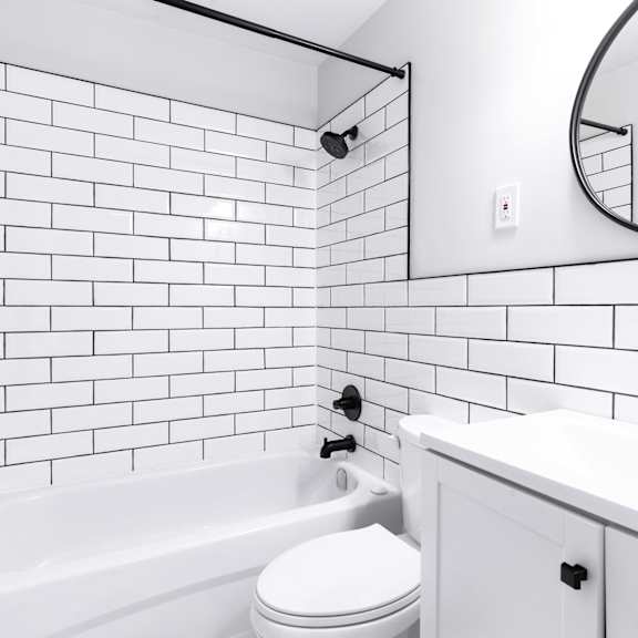 a white bathroom with a black and white tiled shower.
