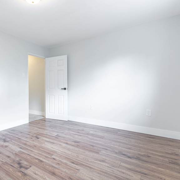 a room with wooden flooring and two white doors.