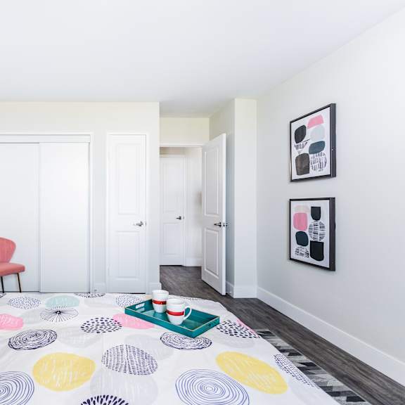 a bedroom with a bed, a chair, and a wall with pictures.