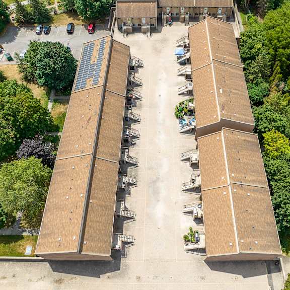 two long buildings with brown roofs are surrounded by trees.