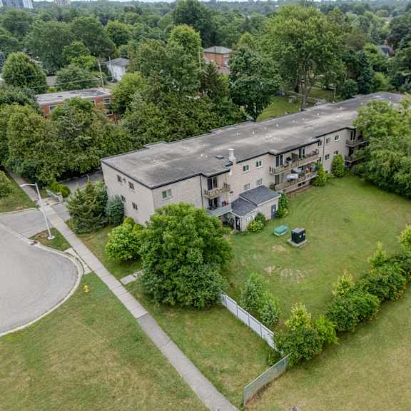 a large house with a green lawn and trees surrounding it.