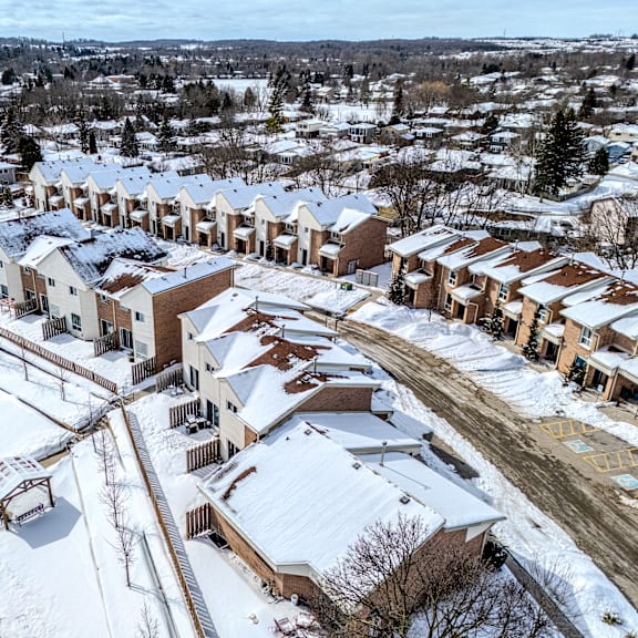 a bird's eye view of a snow-covered residential area with houses and a park.