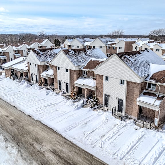 a row of houses with snow on the roofs and driveways.