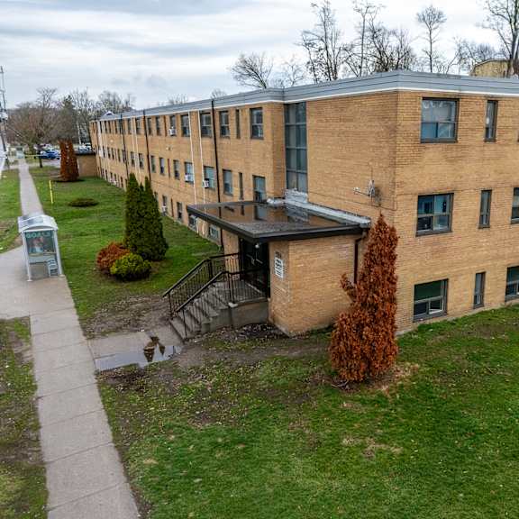 a building with a brown brick exterior and a green lawn in front.