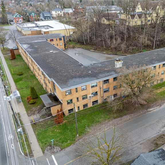a large building with a flat roof is surrounded by a grassy area and trees.