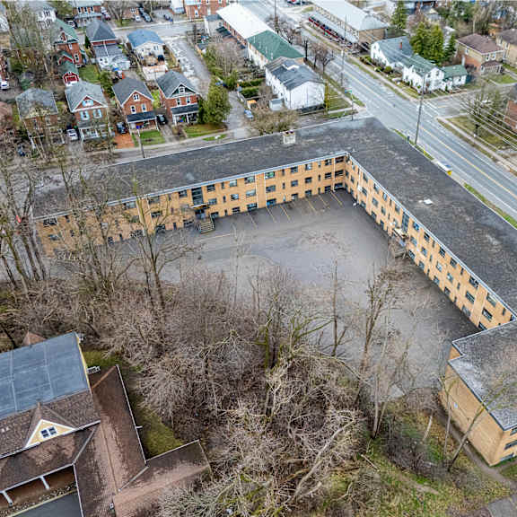 an aerial view of a large, empty, and rundown building with a parking lot in front of it.