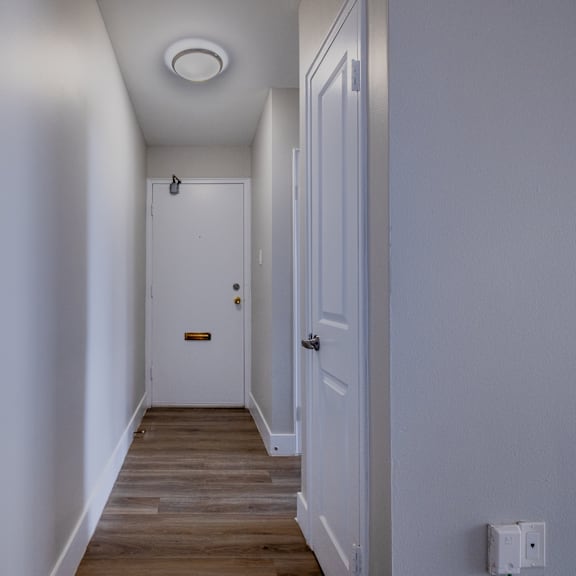 a hallway with a white door and a white wall.