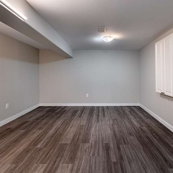 a room with wooden flooring and a window on the right side.