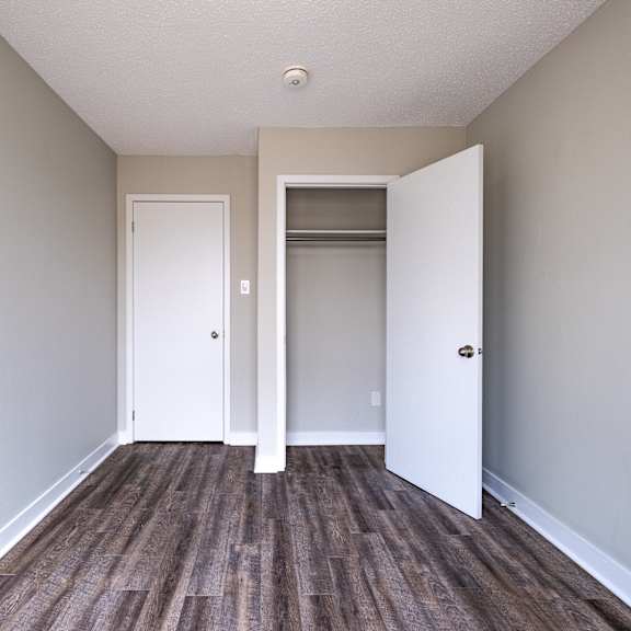 a room with two white doors and a wooden floor.
