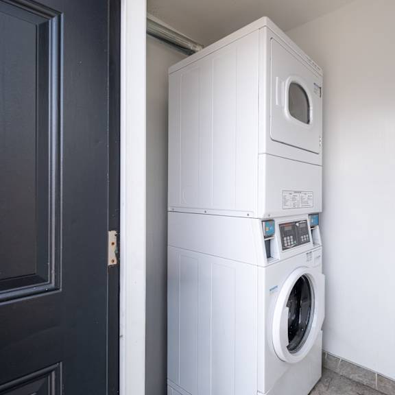 a white washing machine and dryer stacked on top of each other in a small room.