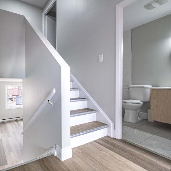 a white staircase with a wooden floor and a white wall.