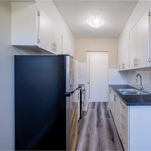 a kitchen with a black refrigerator and white cabinets.
