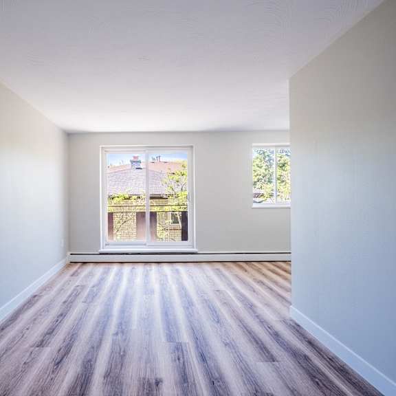 a room with wooden floors and a window showing a balcony.