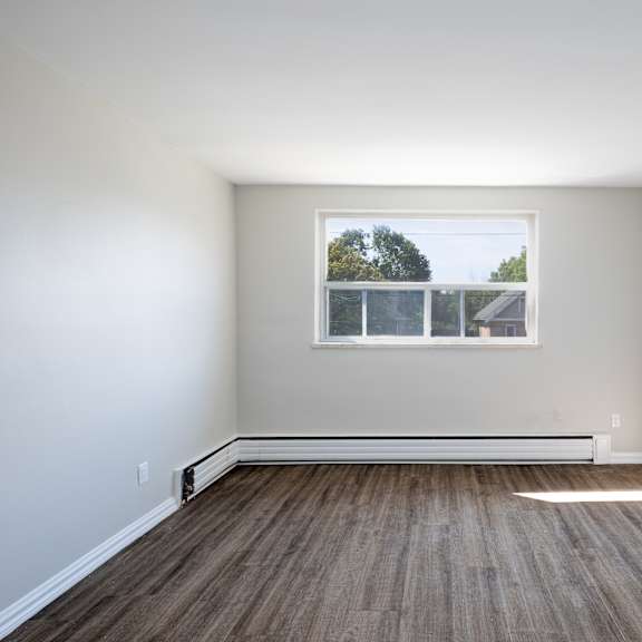 a room with a window and wooden flooring.